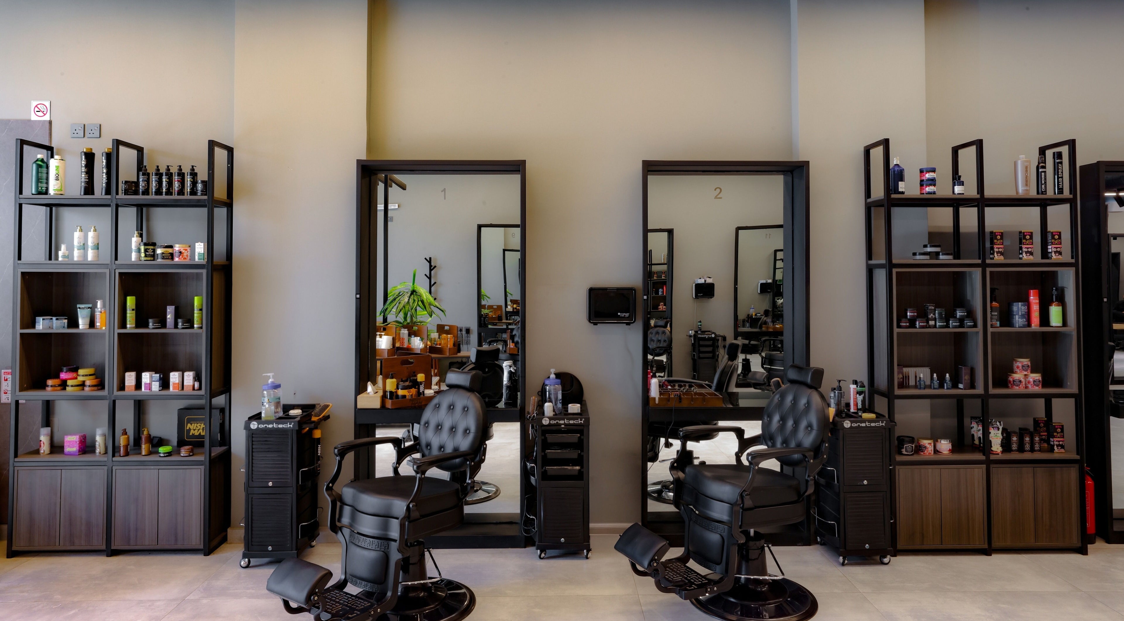 Elegant interior of The Address Barber | صالون العنوان قرطبة, Riyadh, SA with sleek chairs and shelves.