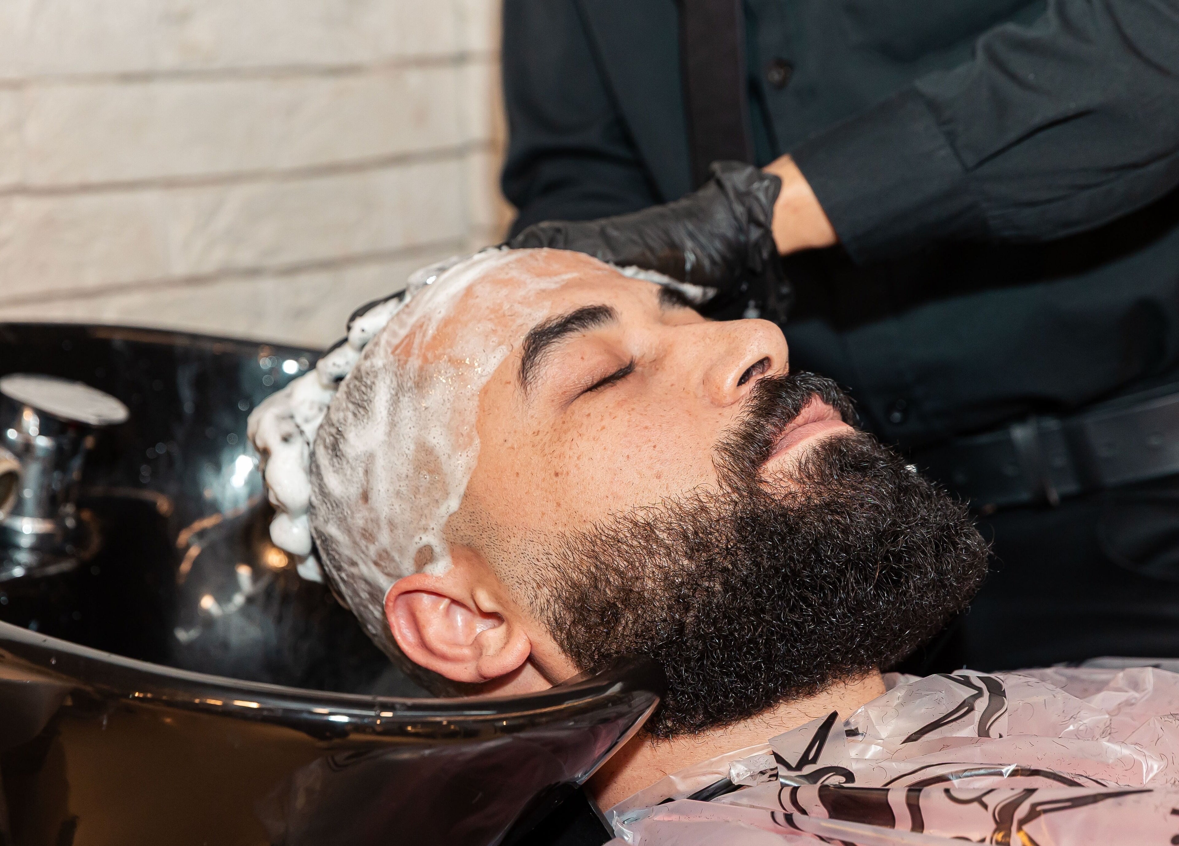 Man enjoying a soothing shampoo at The Address Barber | صالون العنوان اشبيليا, Riyadh, Riyadh Province, SA.