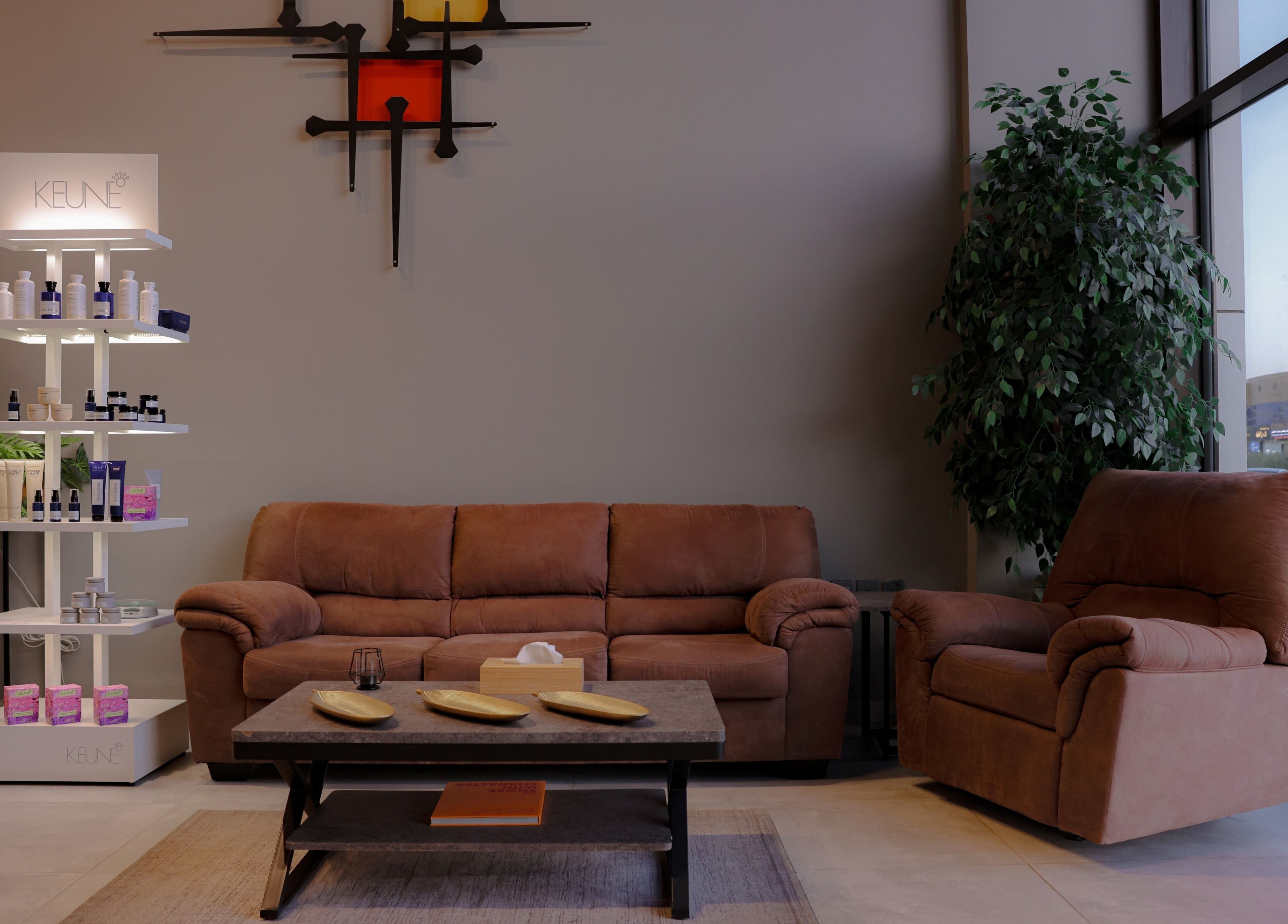 Cozy seating area at The Address Barber | صالون العنوان الملقا, Riyadh, with stylish decor and product display.