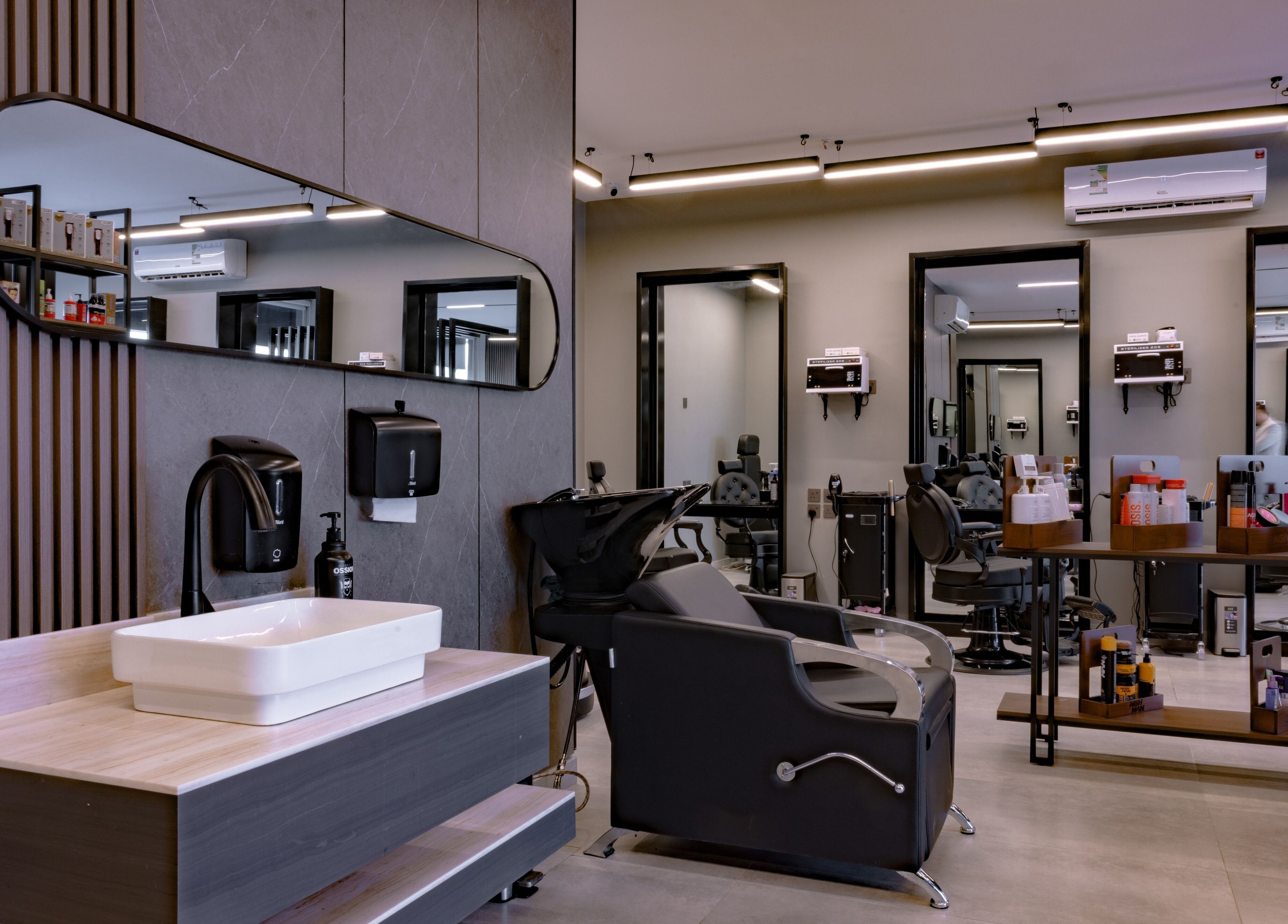Modern interior of The Address Barber | صالون العنوان النزهة in Riyadh, featuring sleek workstations and styling chairs.