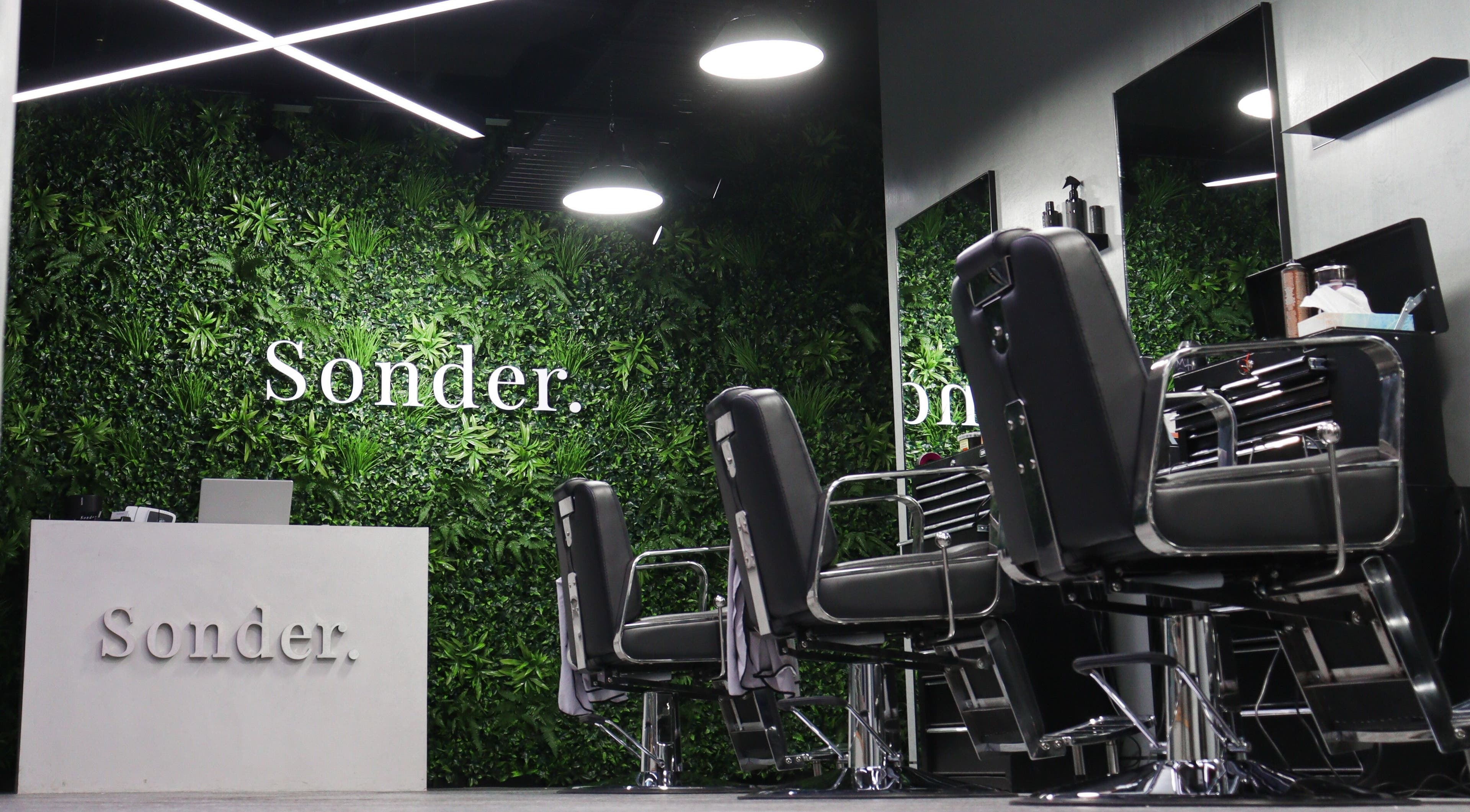 Elegant barber chairs in front of a green wall at Sonder Mens Chatswood, New South Wales, AU.
