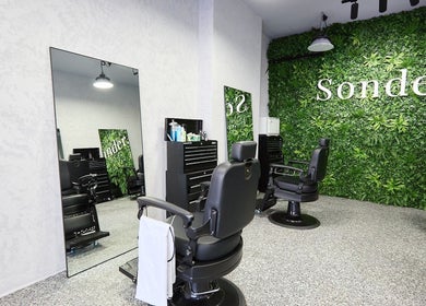 Sleek black barber chairs in front of a green wall at Sonder Mens | Bondi Junction, New South Wales, AU.
