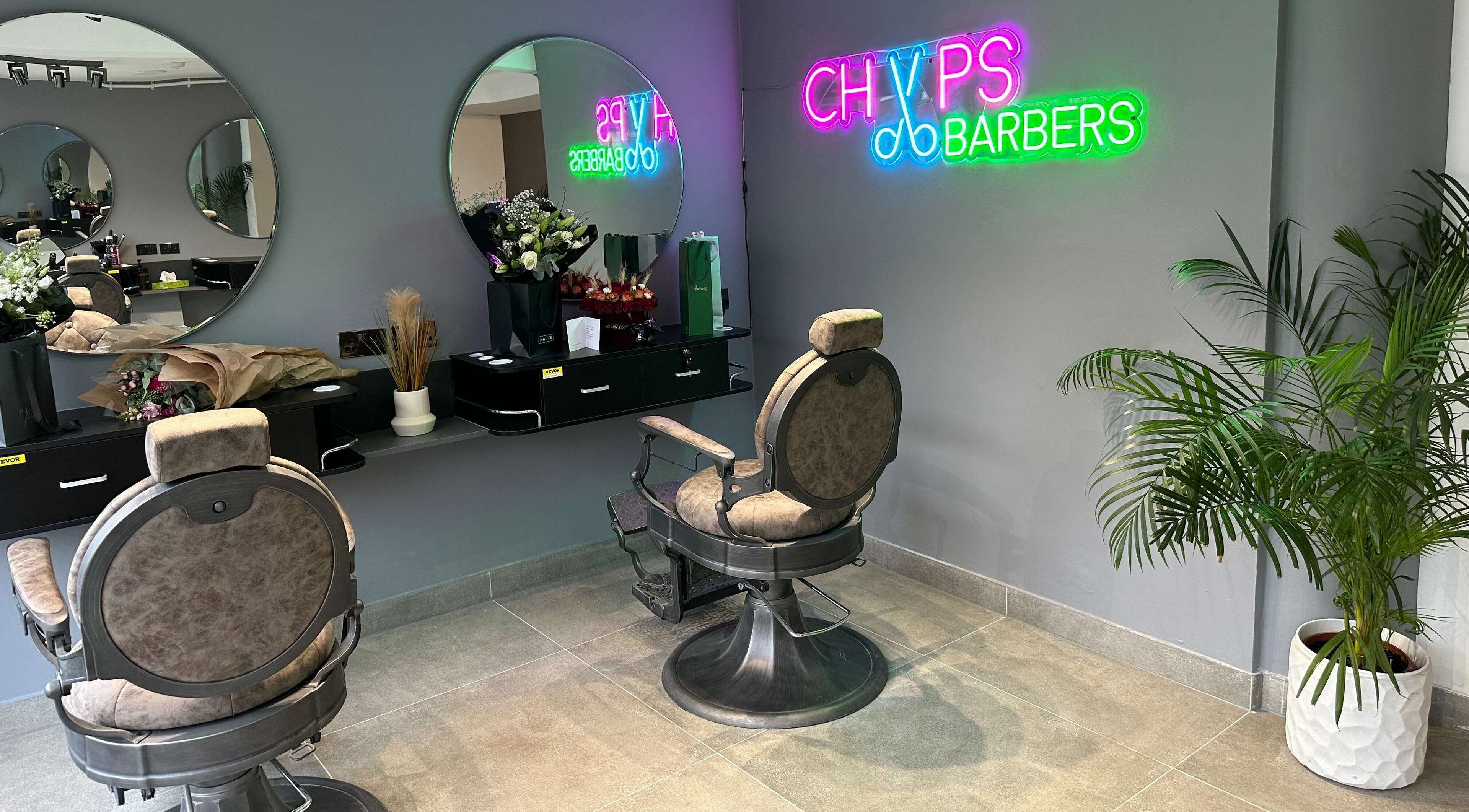 Modern barber chair and neon sign at Chaps Cut in Barnet, England, GB.
