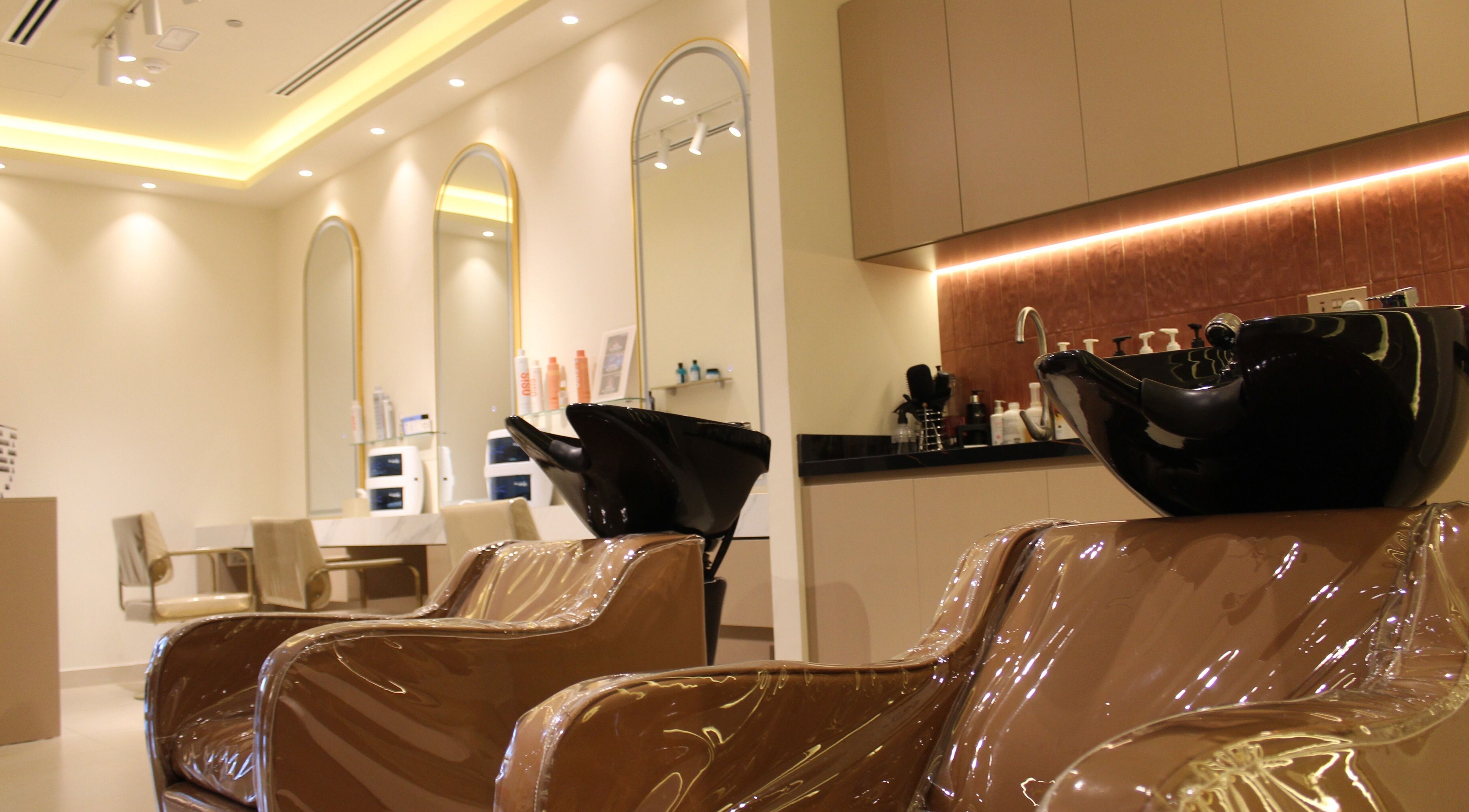 Elegant interior of Sasha Beauty Salon JVC Branch JVC in Dubai, AE, featuring sleek styling chairs and shampoo area.