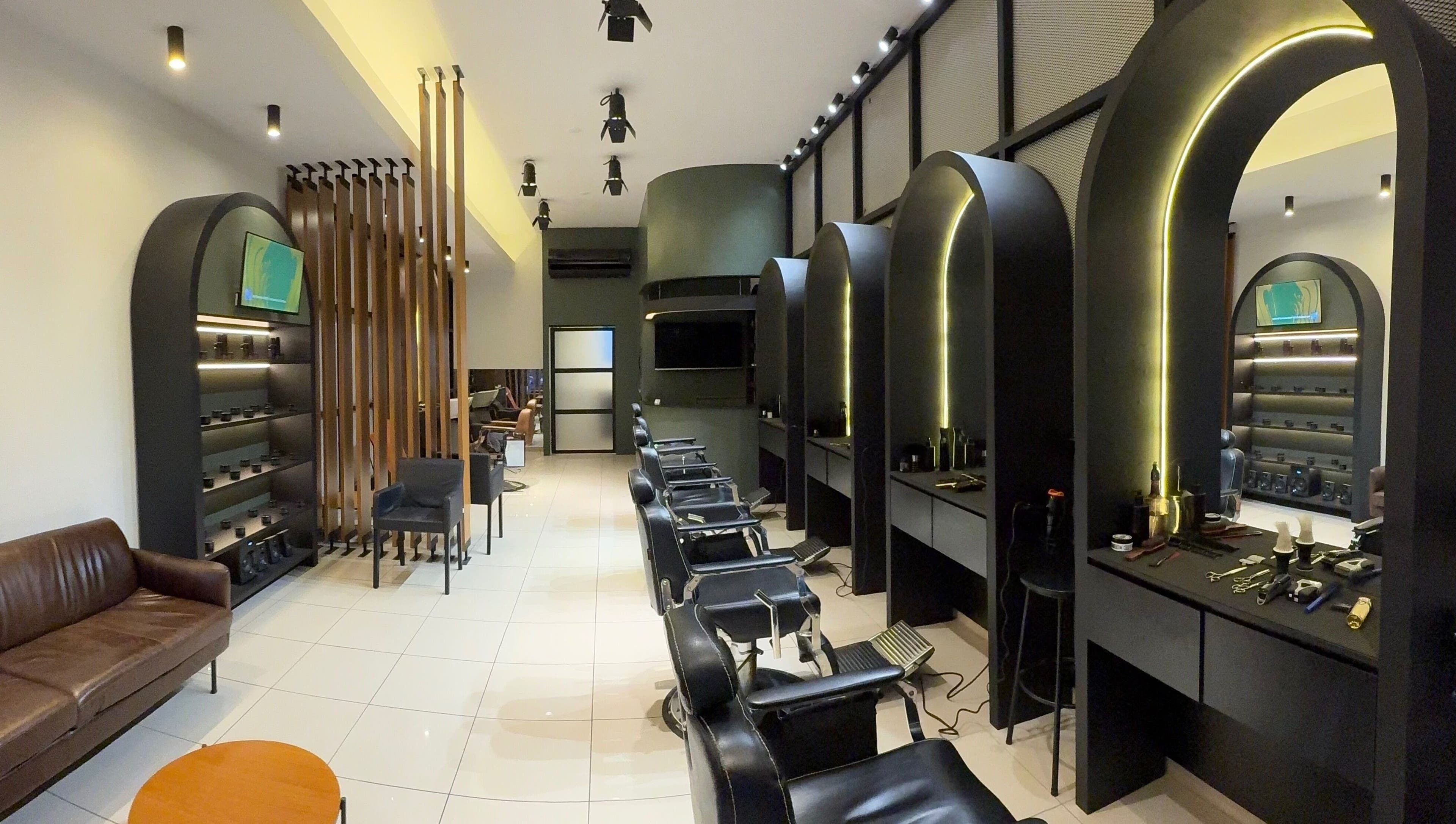 Interior moderno da KÓDEN - Barbearia e Visagismo em Jundiaí, São Paulo, BR, com cadeiras e iluminação estilosa.