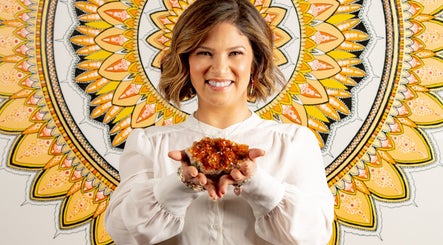 Woman smiling and holding crystal at HoliSoi / HoliSelf, Montréal, Québec, CA against a mandala backdrop.