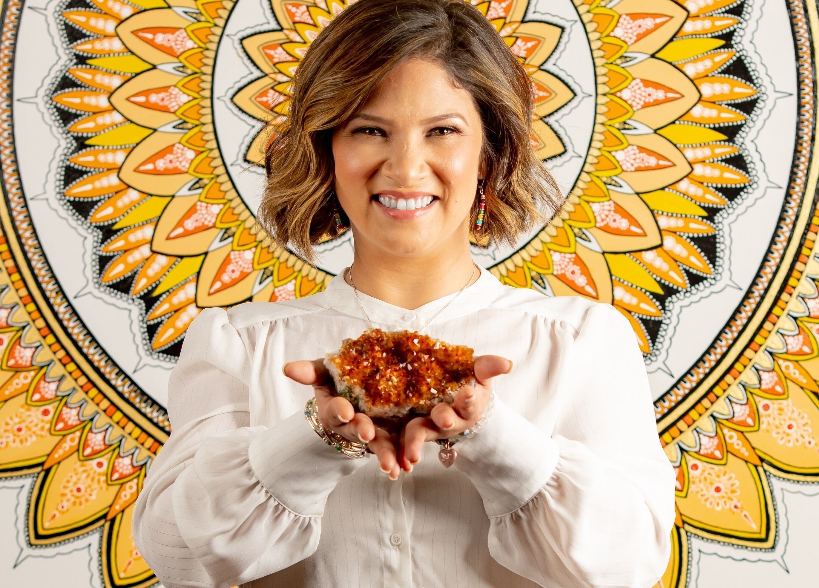 Smiling person holding crystal in front of mandala at HoliSoi/HoliSelf, Montréal, Québec, CA.