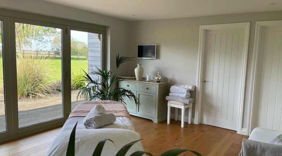 Tranquil spa room at KD Wellness Retreat, Bristol, England, GB with massage bed and garden view.