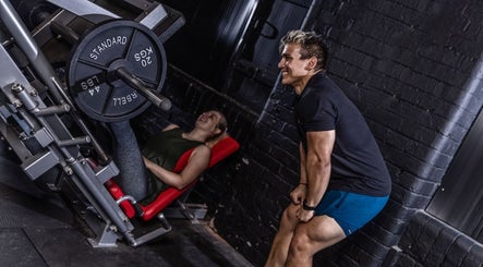 Personal trainer assisting client during leg press at Kiwi Personal Training, Manchester, England, GB.