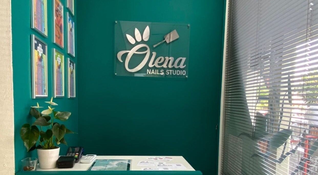 Вход в Olena nails studio в Любляне. Дизайн интерьера с зелеными стенами и растением.