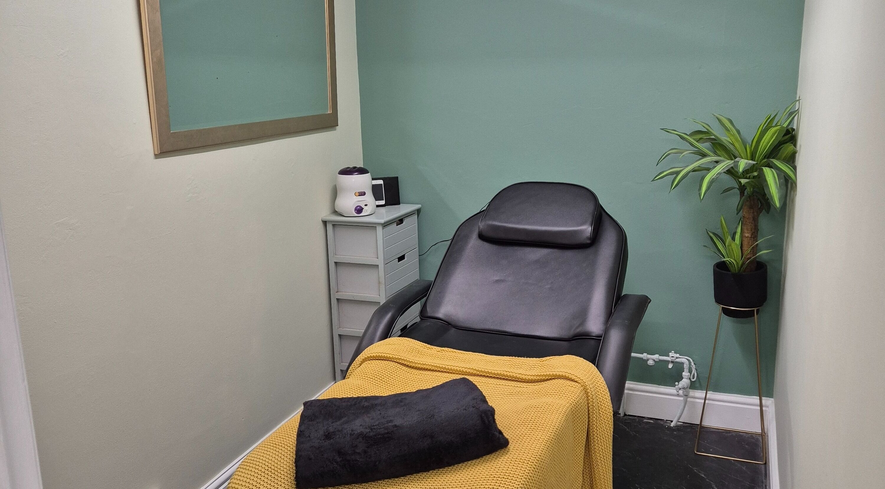 Relaxing spa room at The Green Lounge, Haughley, England, GB with a cozy chair and a potted plant.