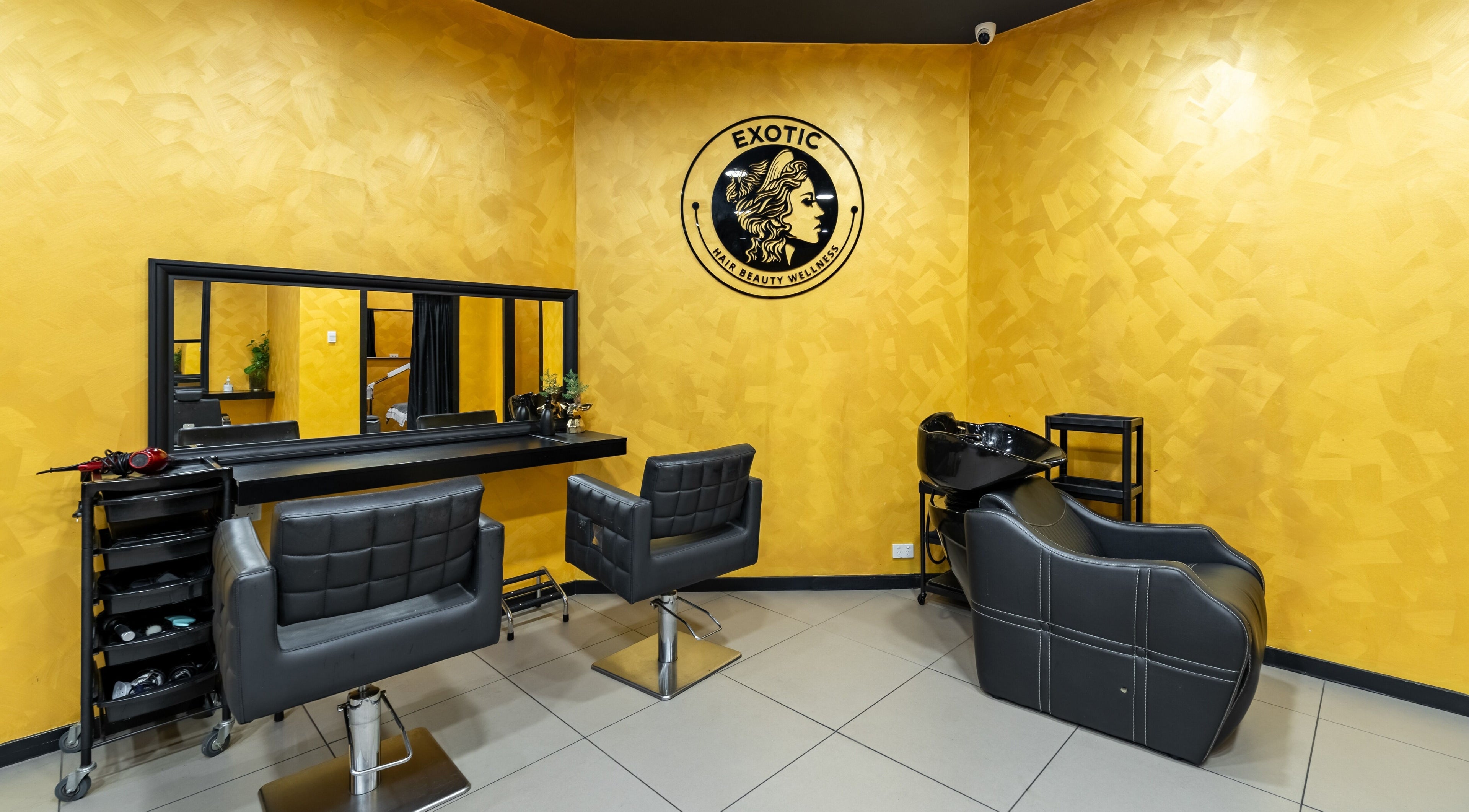 Modern interior of Exotic Indian Salon Richmond, New South Wales, AU with sleek black chairs against a vibrant yellow wall.