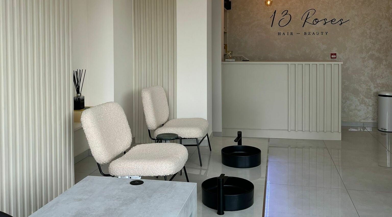 Modern salon seating area at 13 Roses, London, England, GB, featuring elegant decor and comfortable chairs.
