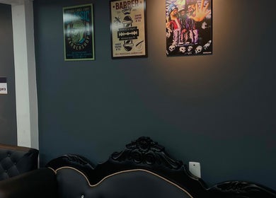 Sala de espera en Barberia Full HD, Bogotá, CUNDINAMARCA, CO, con sofás elegantes y carteles de barbería.