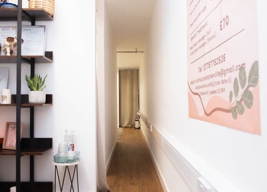 Calming hallway at Paul Sri, London, England, GB with decor and awards on display shelves.