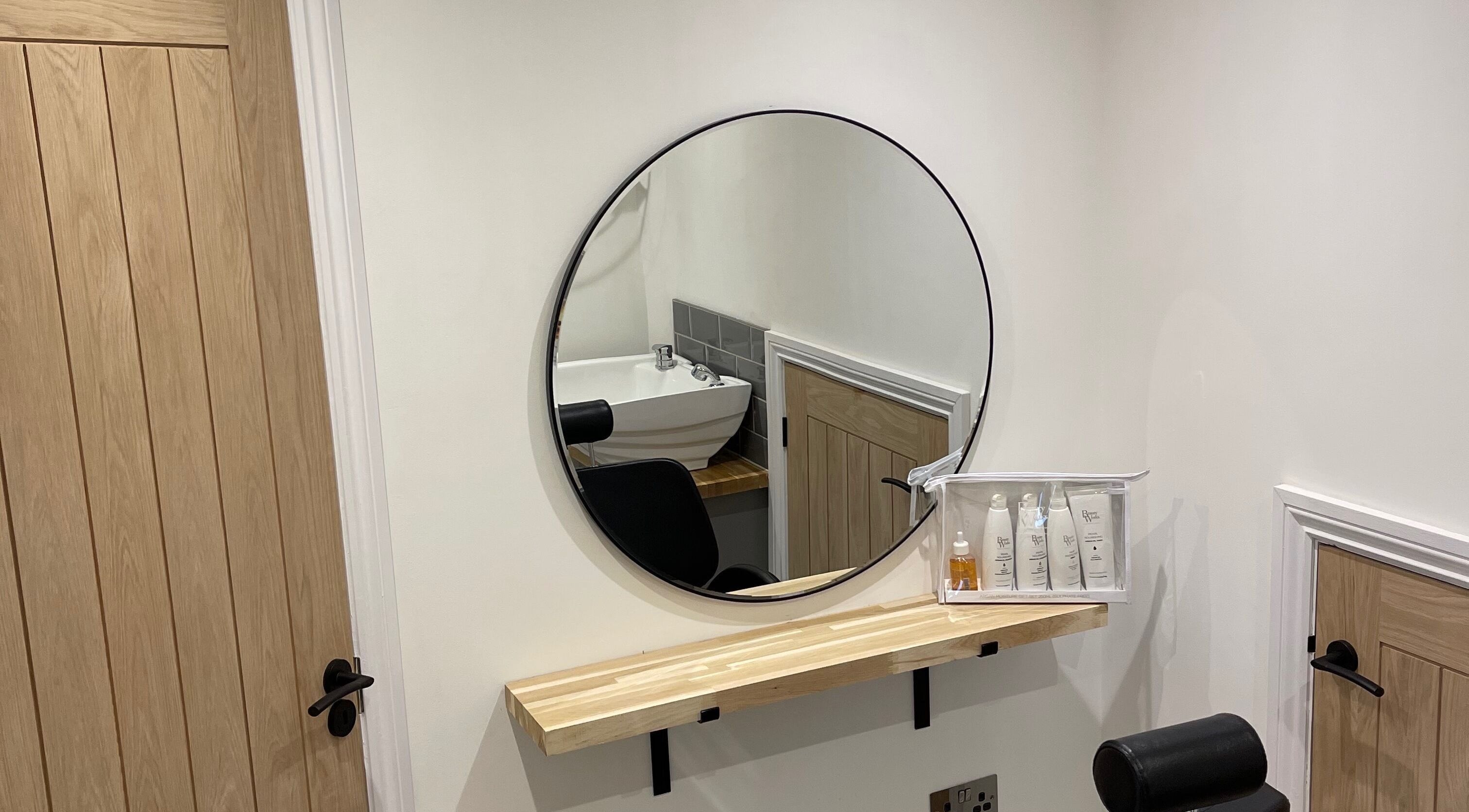 Modern salon corner at Natalie Mae Hair in Sturminster Newton, England, GB featuring a round mirror and sink.