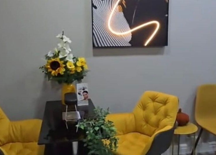 Cozy, modern waiting area at Professional Enhancements in Lytham St Annes, England, with yellow chairs and floral decor.