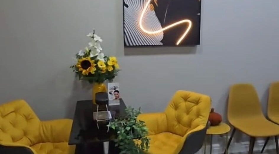 Cozy, modern waiting area at Professional Enhancements in Lytham St Annes, England, with yellow chairs and floral decor.