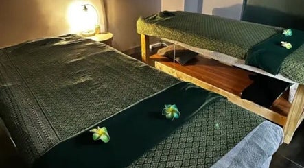 Cozy massage beds at Elegant Thai Massage in Melbourne, Australia, AU with dim lighting and decorative flowers.