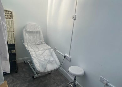 Effortless beauty treatment room in London, England, GB, featuring a comfortable treatment chair and stool.