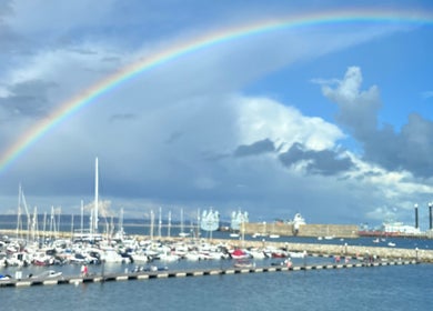 A vibrant rainbow arches over a serene harbor near The Beauty Deck in Portland, England, GB.