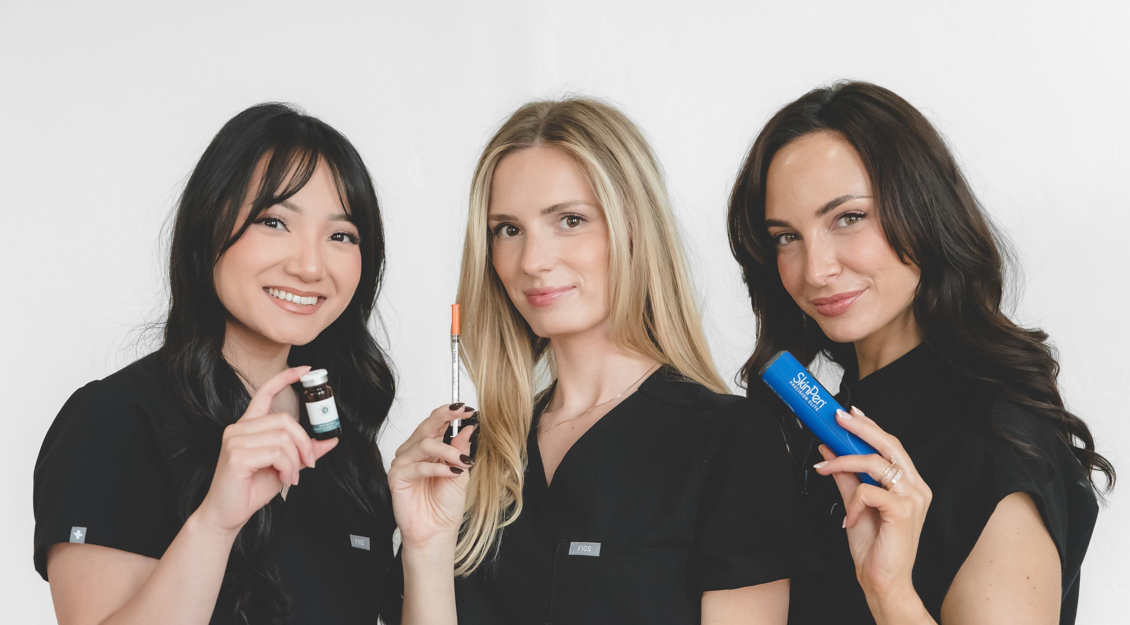 Three beauty experts at Wagner Aesthetic Studio in De Pere, Wisconsin, US holding skincare products.