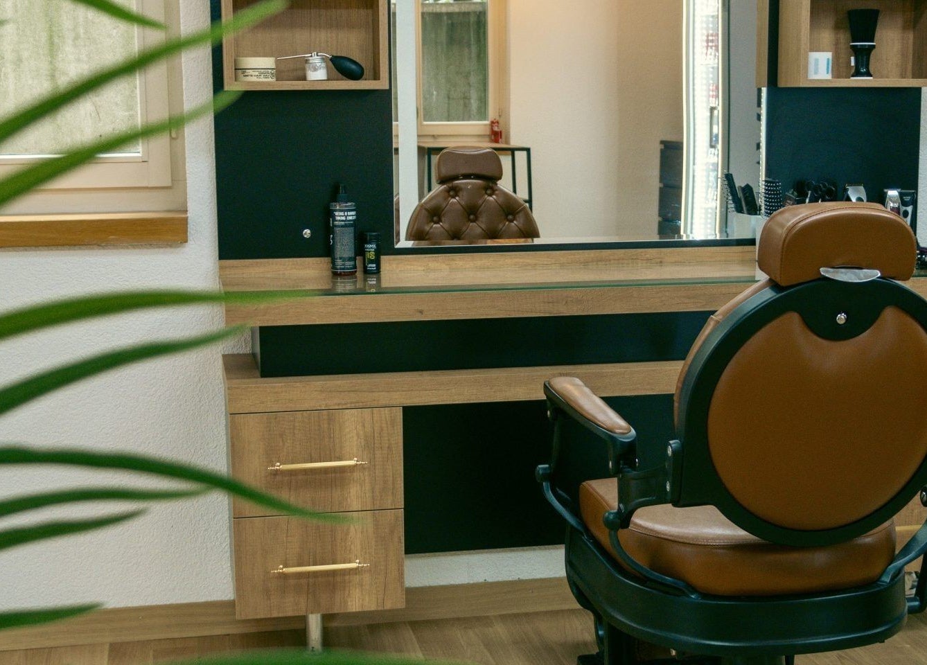 Ein stilvoller Stuhl im Ali Barber Shop Bern, Bern, CH, umgeben von modernen Holzmöbeln und Spiegeln.