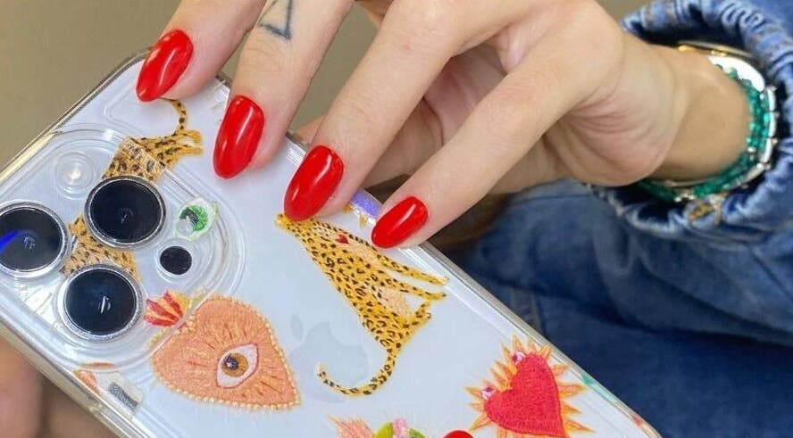 Red manicured nails holding a phone case at European Beauty in Everett, Washington, US.