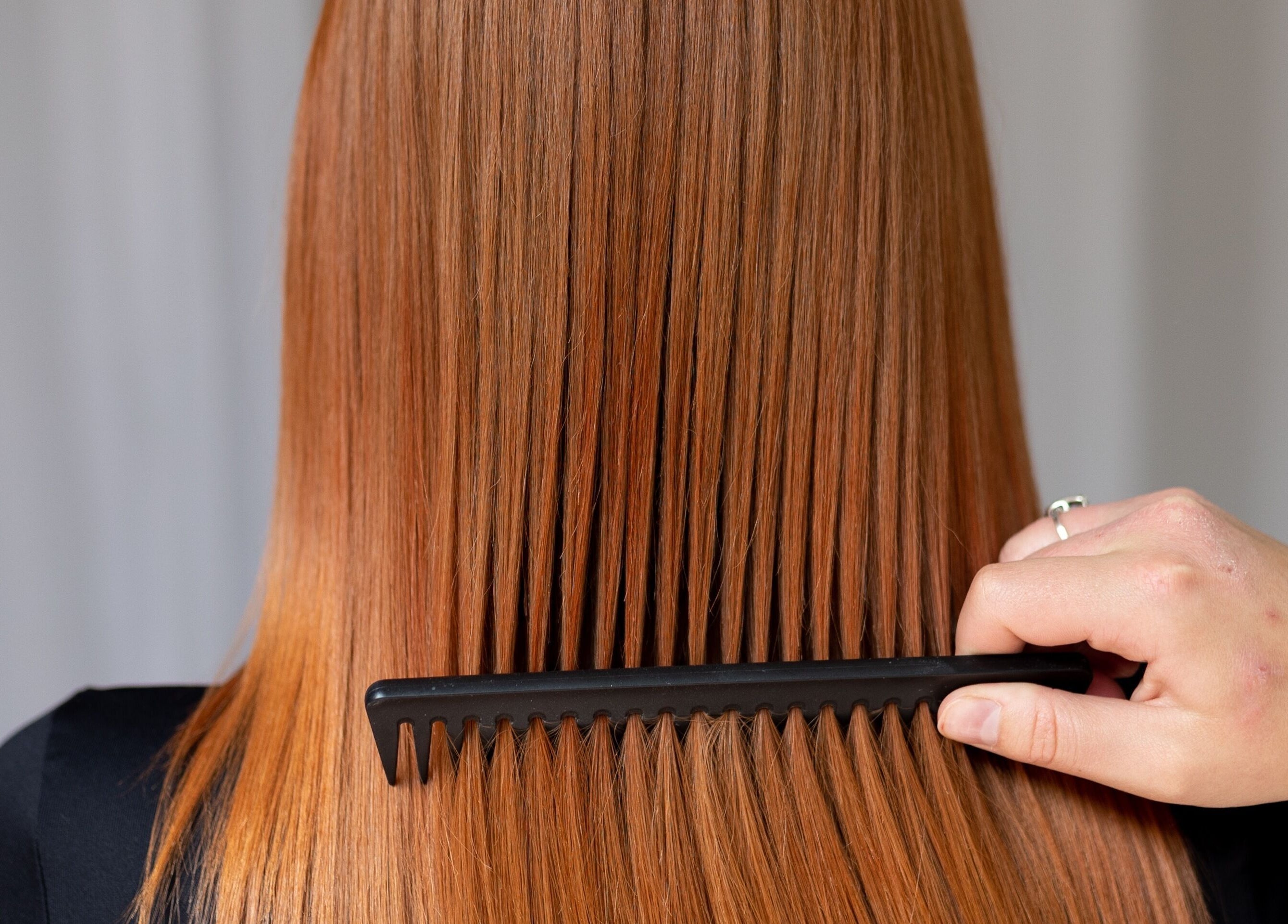 Stylist combing smooth red hair at Hair By Alicia Louise, Warragul, Victoria, AU salon.