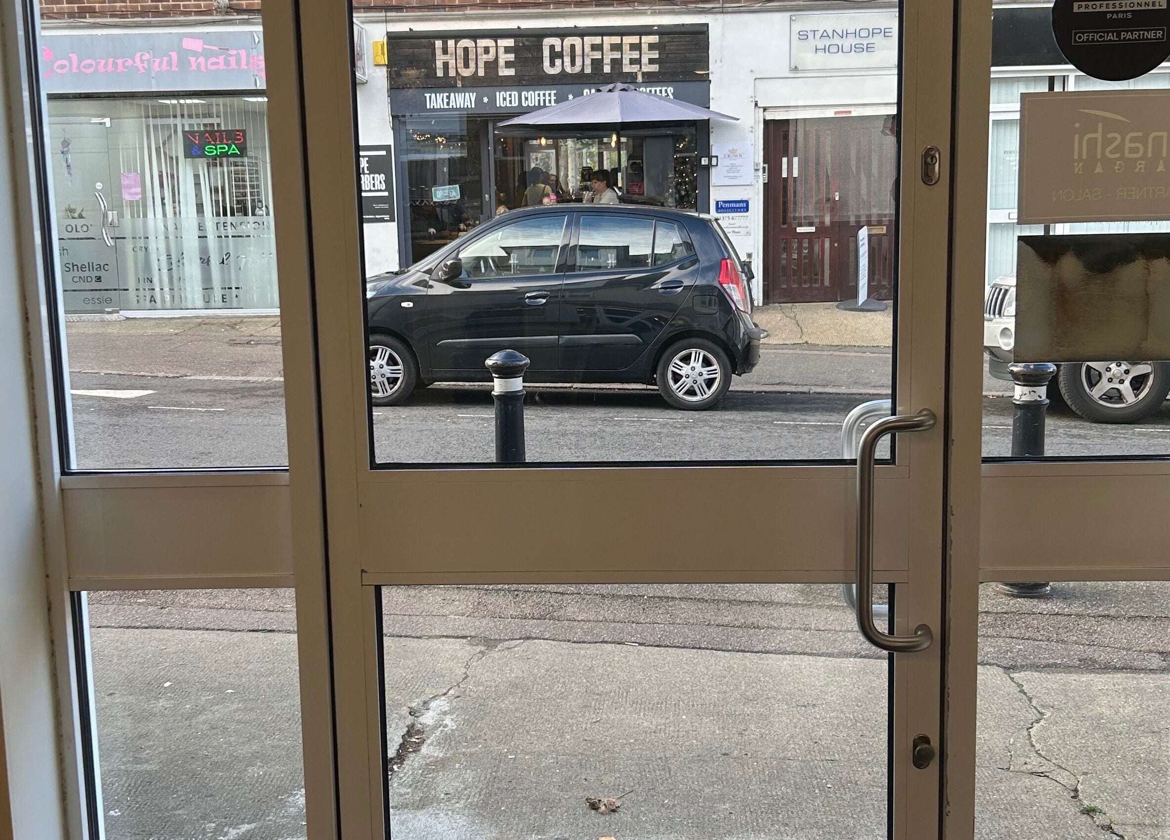 View through Beautify's entrance in Stanford-le-Hope, England, GB showing nearby coffee shop.