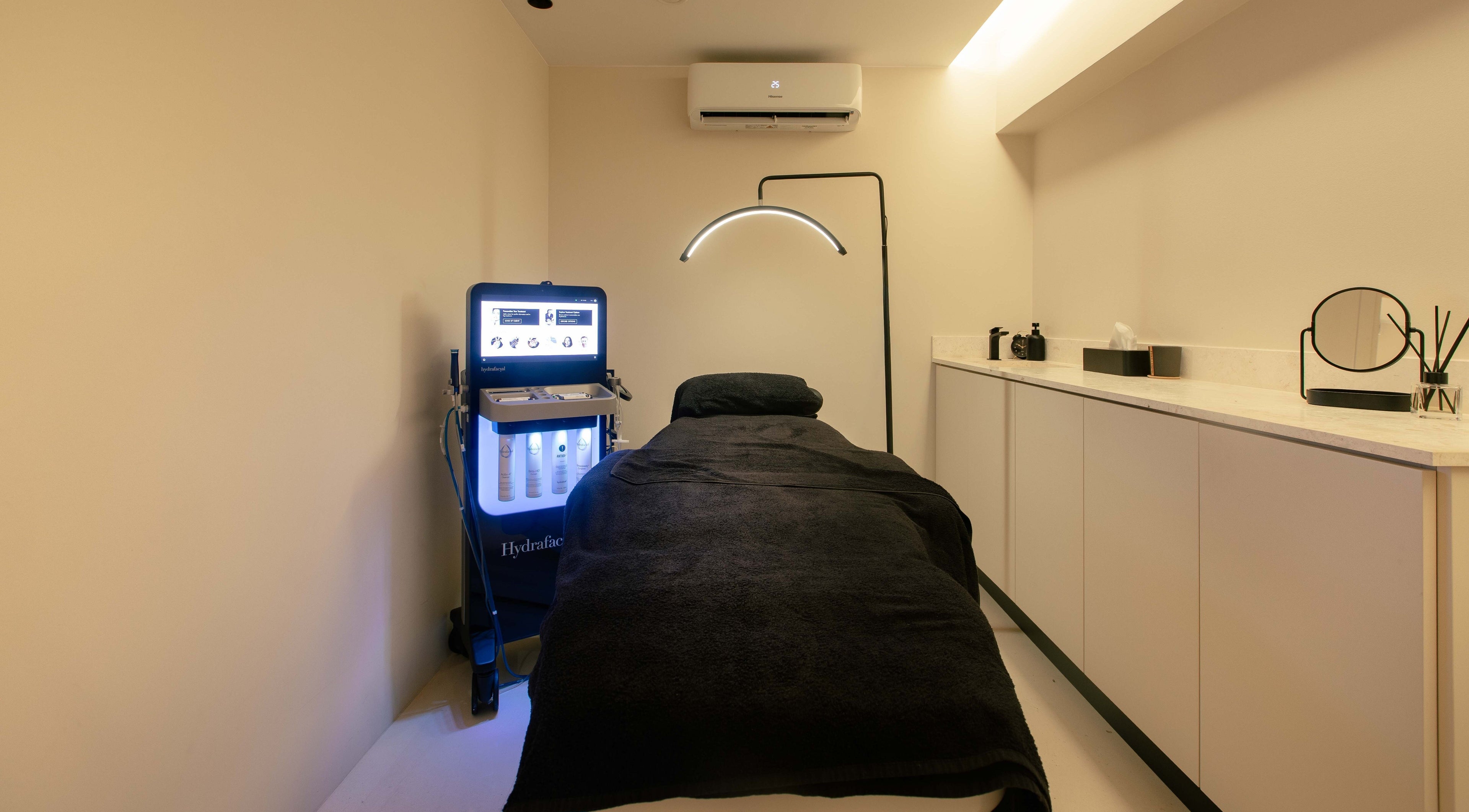 Δωμάτιο θεραπείας στο Skinu Premium Cosmetics, Αθήνα, GR με εξοπλισμό και μαύρα σεντόνια.