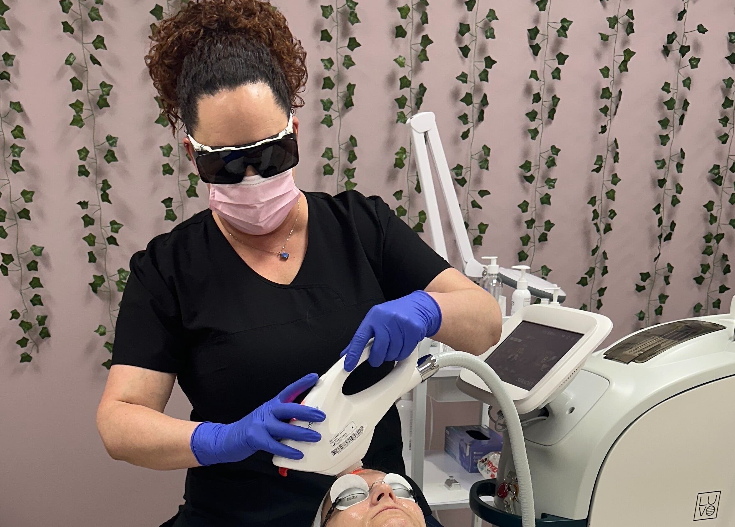 Expert at Derma Defined Esthetics performs skincare treatment in High River, Alberta, CA. Modern equipment visible.