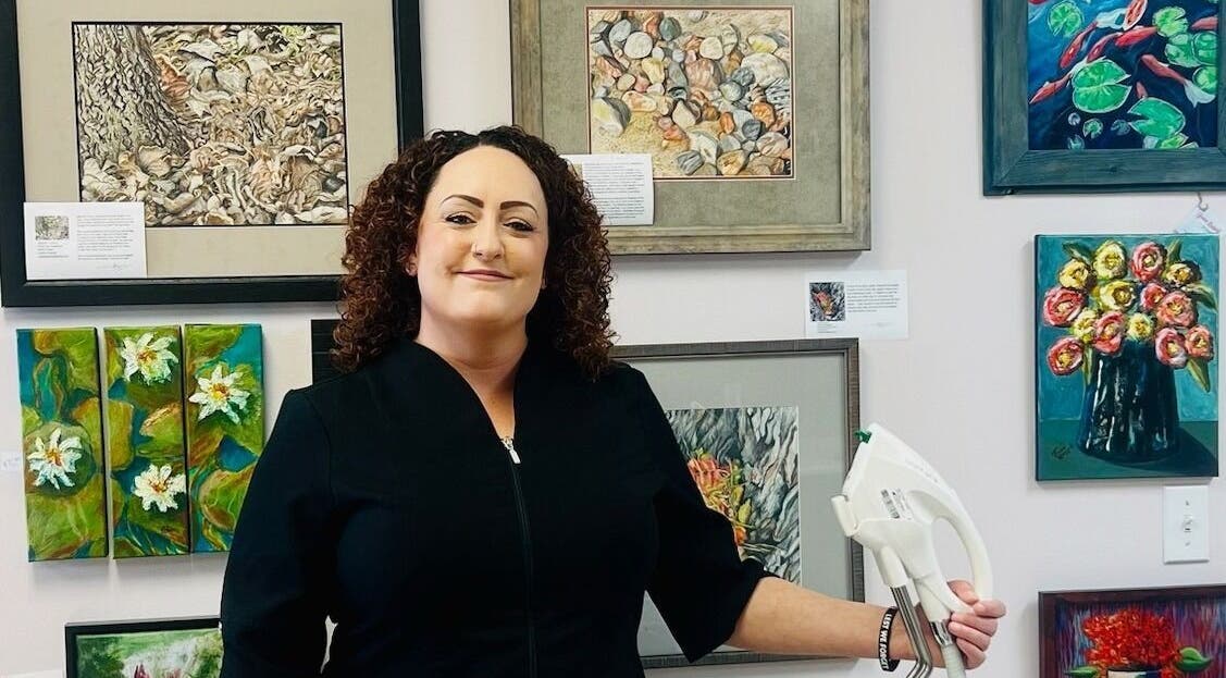 Aesthetician at Derma Defined Esthetics in High River, Alberta, CA, surrounded by vibrant artwork.
