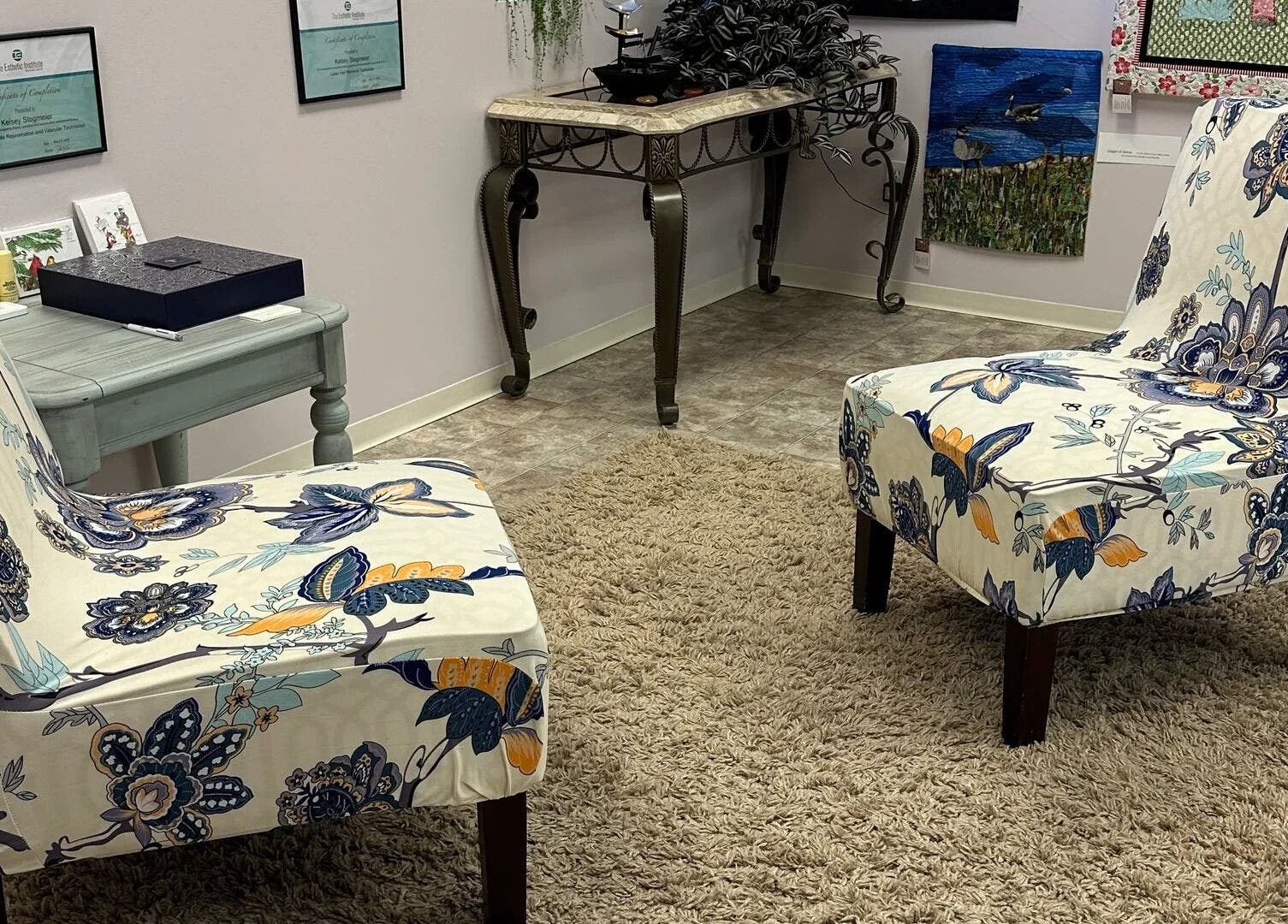 Elegant seating area at Derma Defined Esthetics, High River, Alberta, CA with floral chairs and art decor.