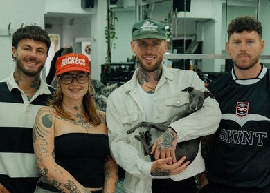 Team at Masters Barbershop, Brighton and Hove, England, GB, smiling indoors with a dog.