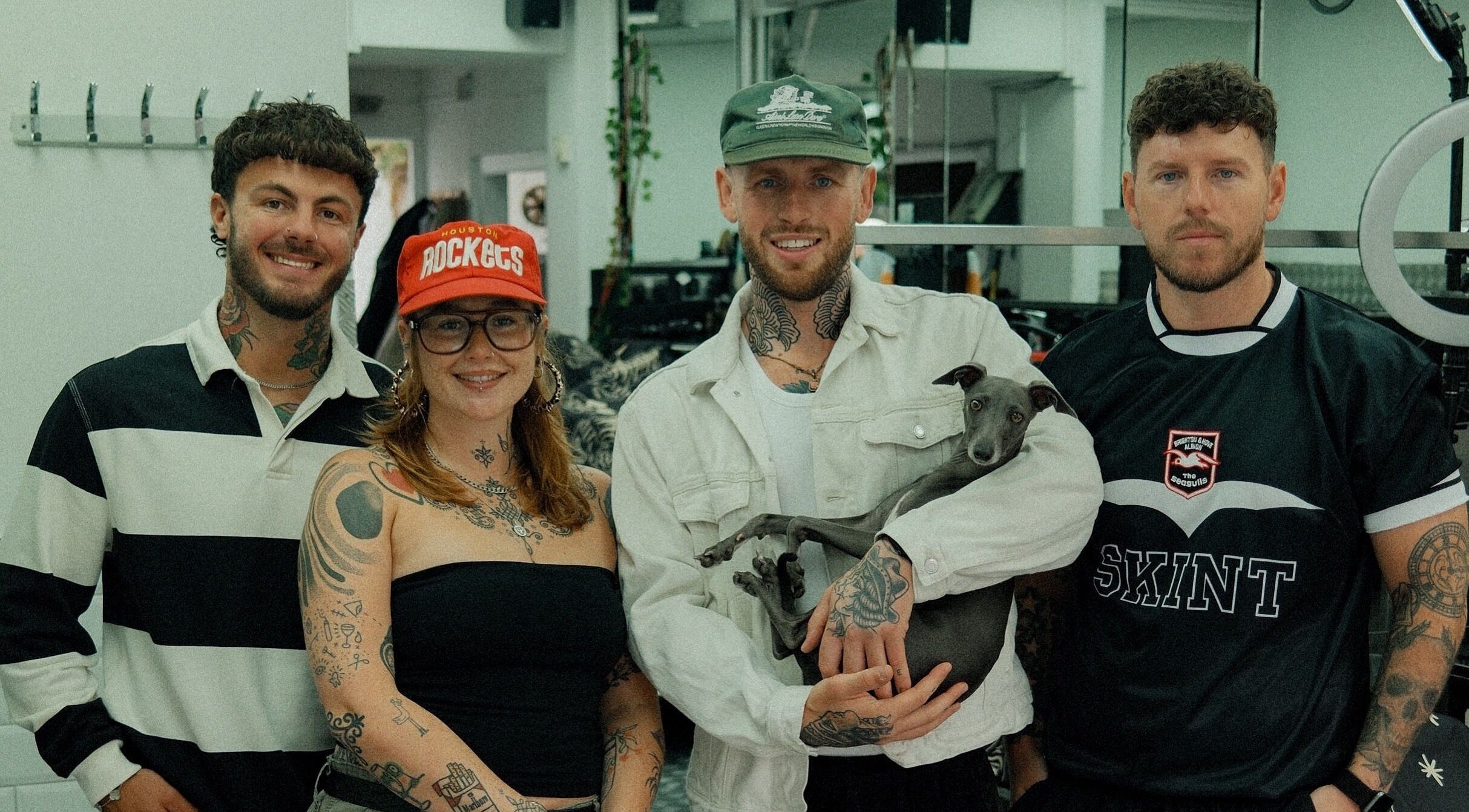 Team at Masters Barbershop, Brighton and Hove, England, GB, smiling indoors with a dog.
