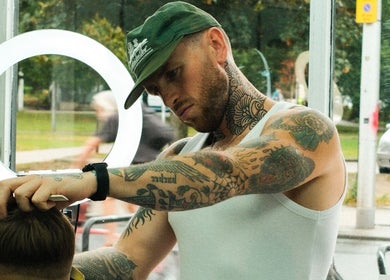 Tattooed barber styling hair at Masters Barbershop, Brighton and Hove, England, GB.