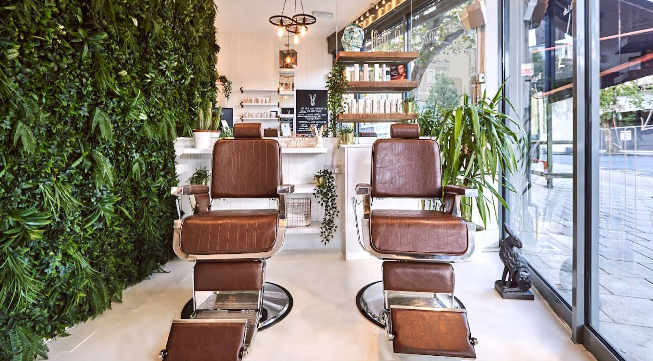 Interior of Naked Hare in London, England, GB featuring stylish brown salon chairs with lush greenery.