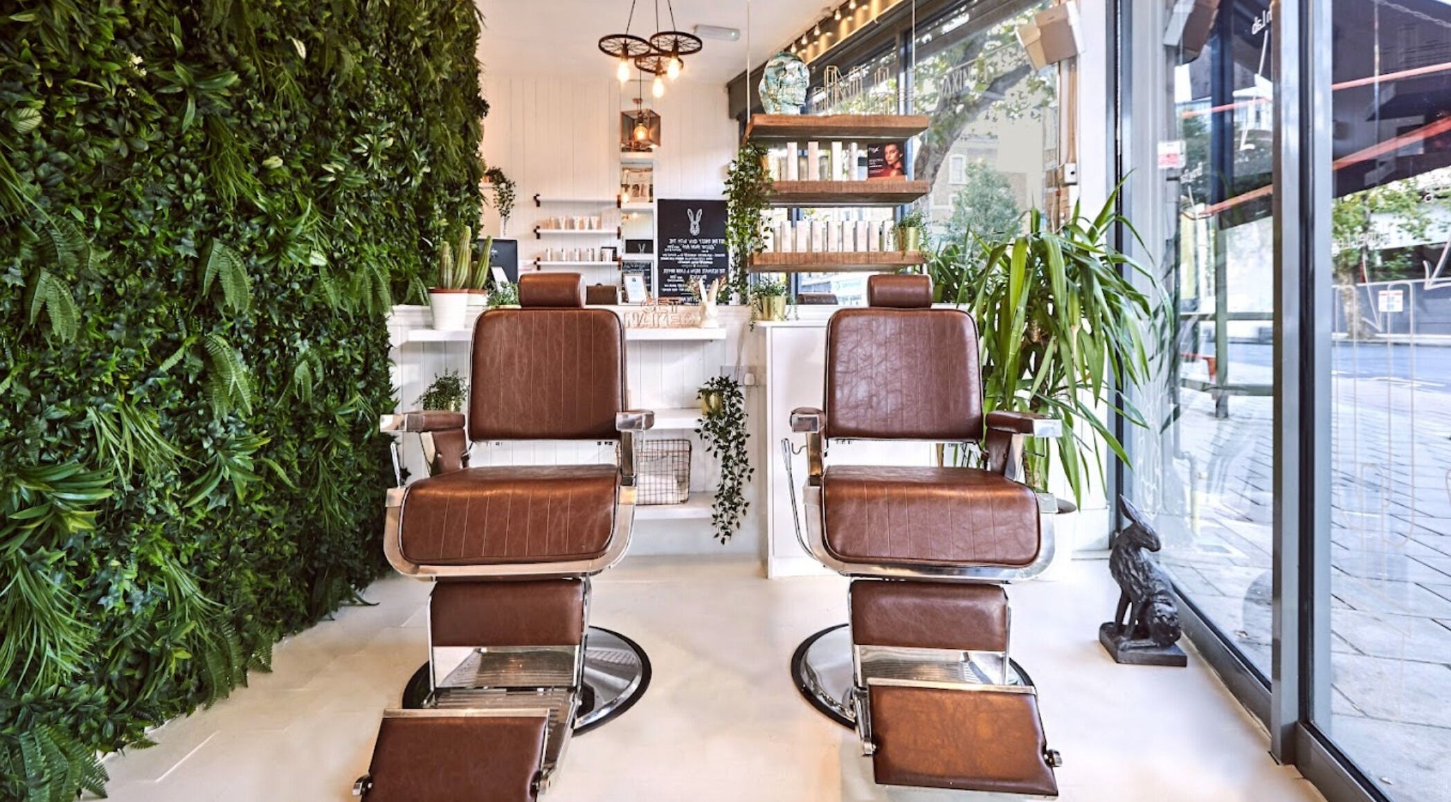 Interior of Naked Hare in London, England, GB featuring stylish brown salon chairs with lush greenery.