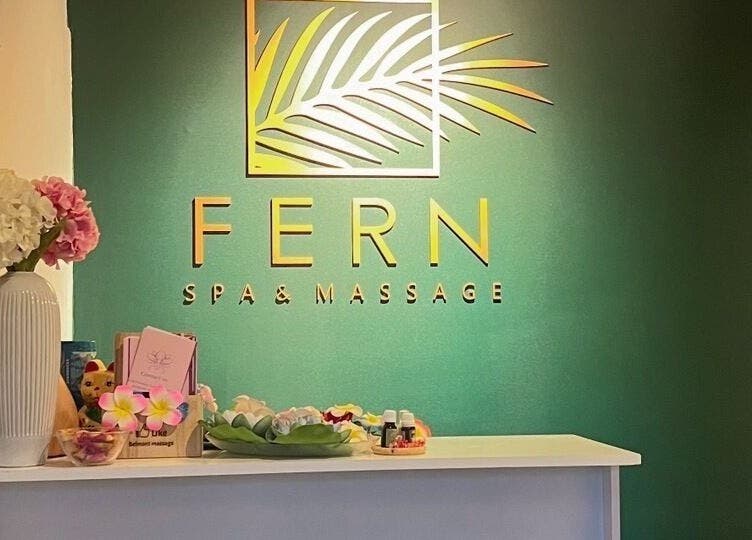 Reception of Fern Spa & Massage in Auckland, NZ. Elegant decor with a green wall and floral accents.