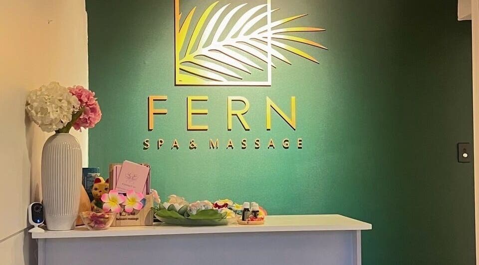 Reception of Fern Spa & Massage in Auckland, NZ. Elegant decor with a green wall and floral accents.