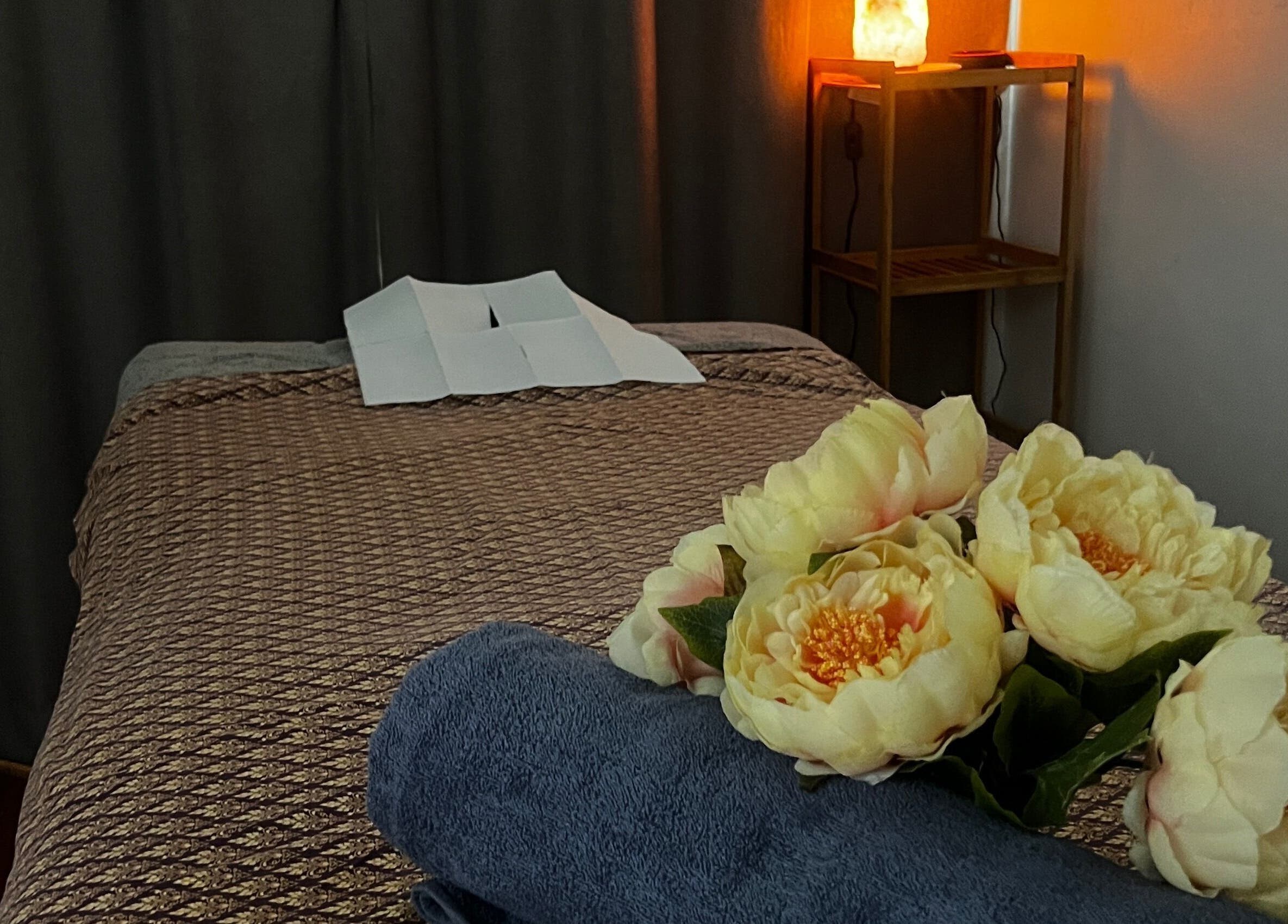 Relaxing massage bed at Fern Spa & Massage in Auckland, Auckland, NZ with soft lighting and floral decor.