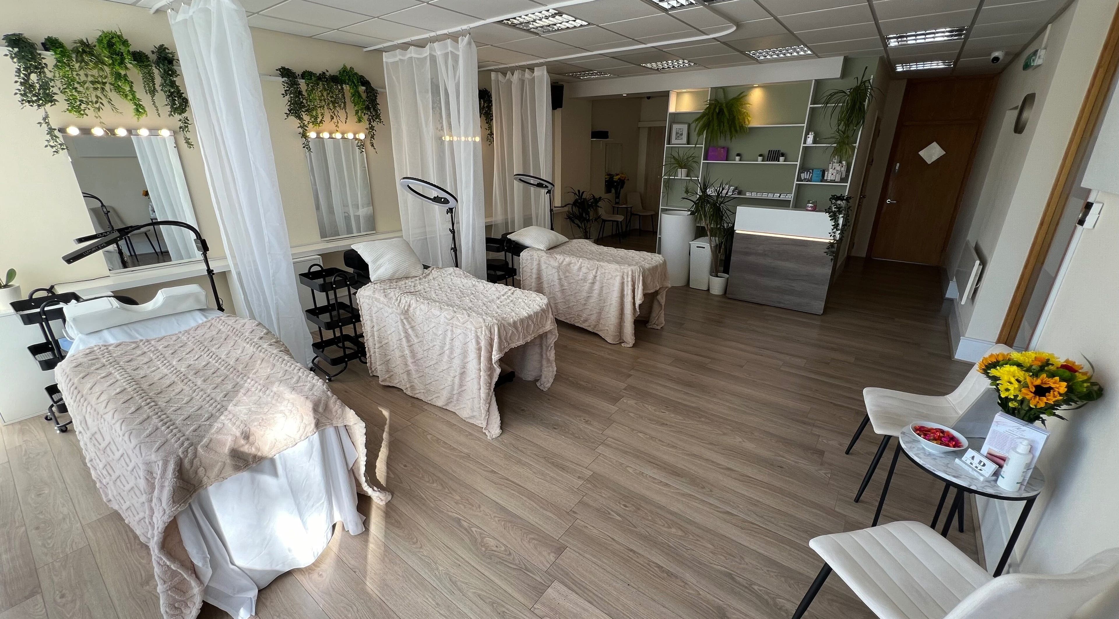 Tranquil treatment room at Magnolia Beauty and Beyond, Norwich, England, GB, with cozy beds and lush greenery.