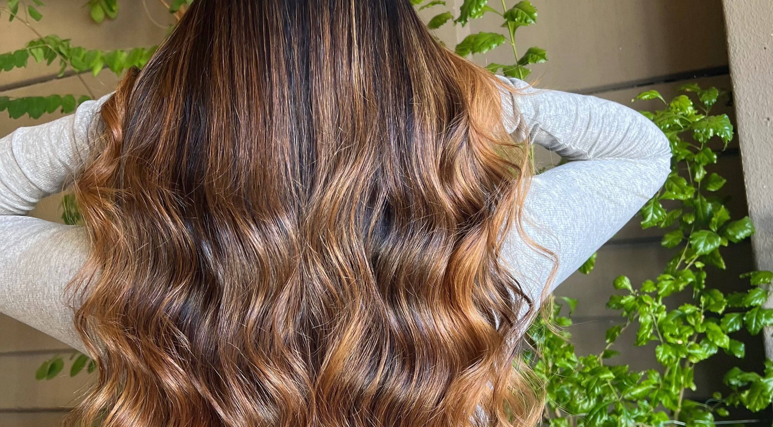 Flowing wavy hair transformation at Cpt Hairn, Cape Town, Western Cape, ZA, embraced by green plants.