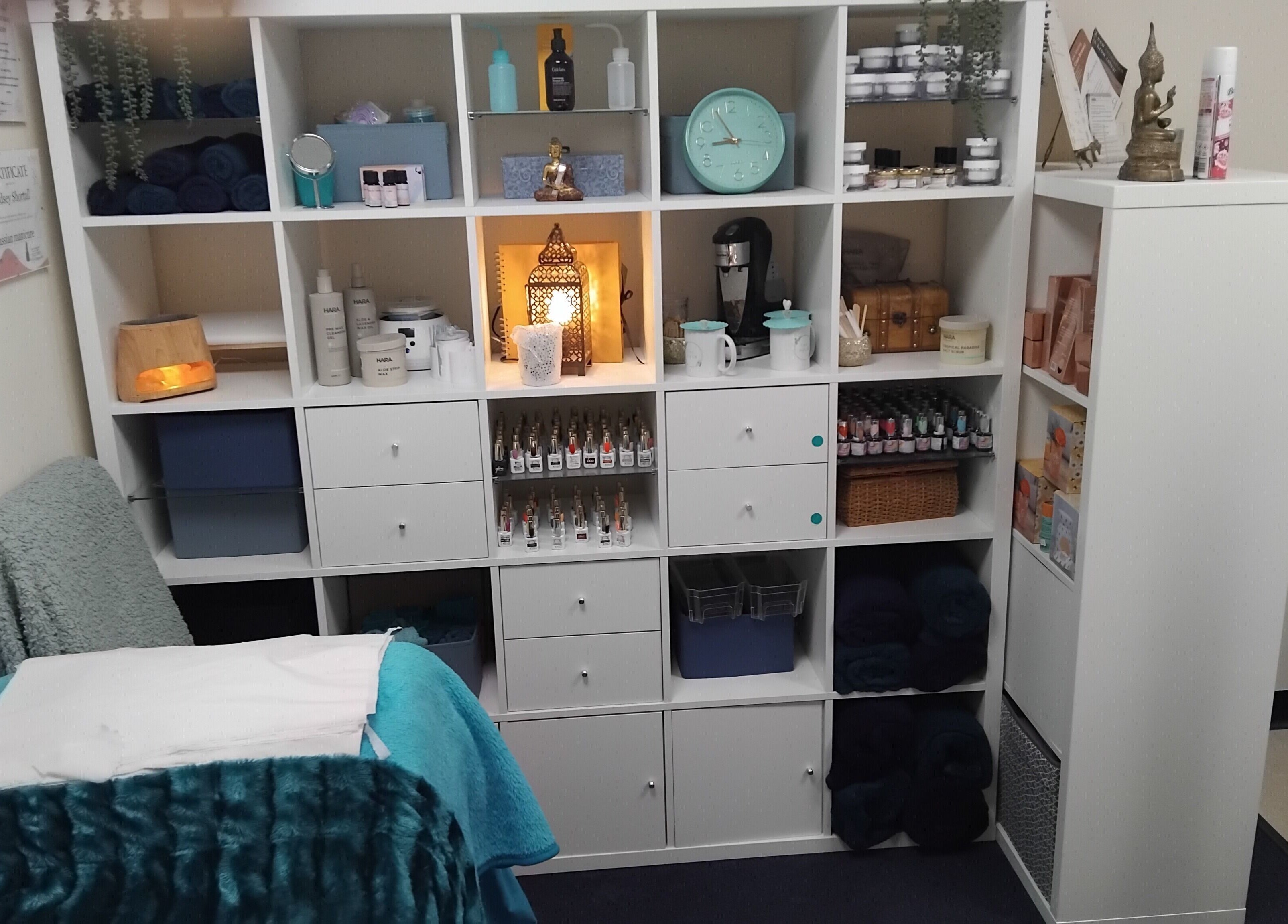 Cozy treatment room at The Nook, Ellesmere Port, England, GB with organized shelves and a comfy bed.