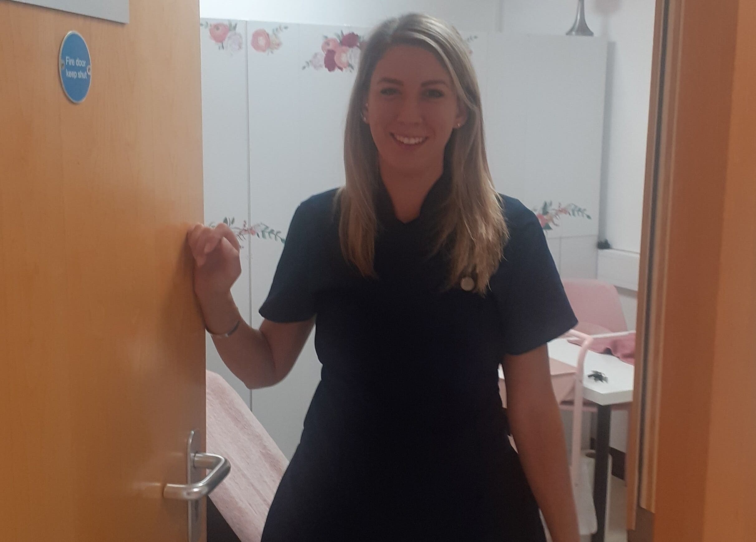 Friendly staff member at The Nook, Ellesmere Port, England, GB standing at a treatment room door.