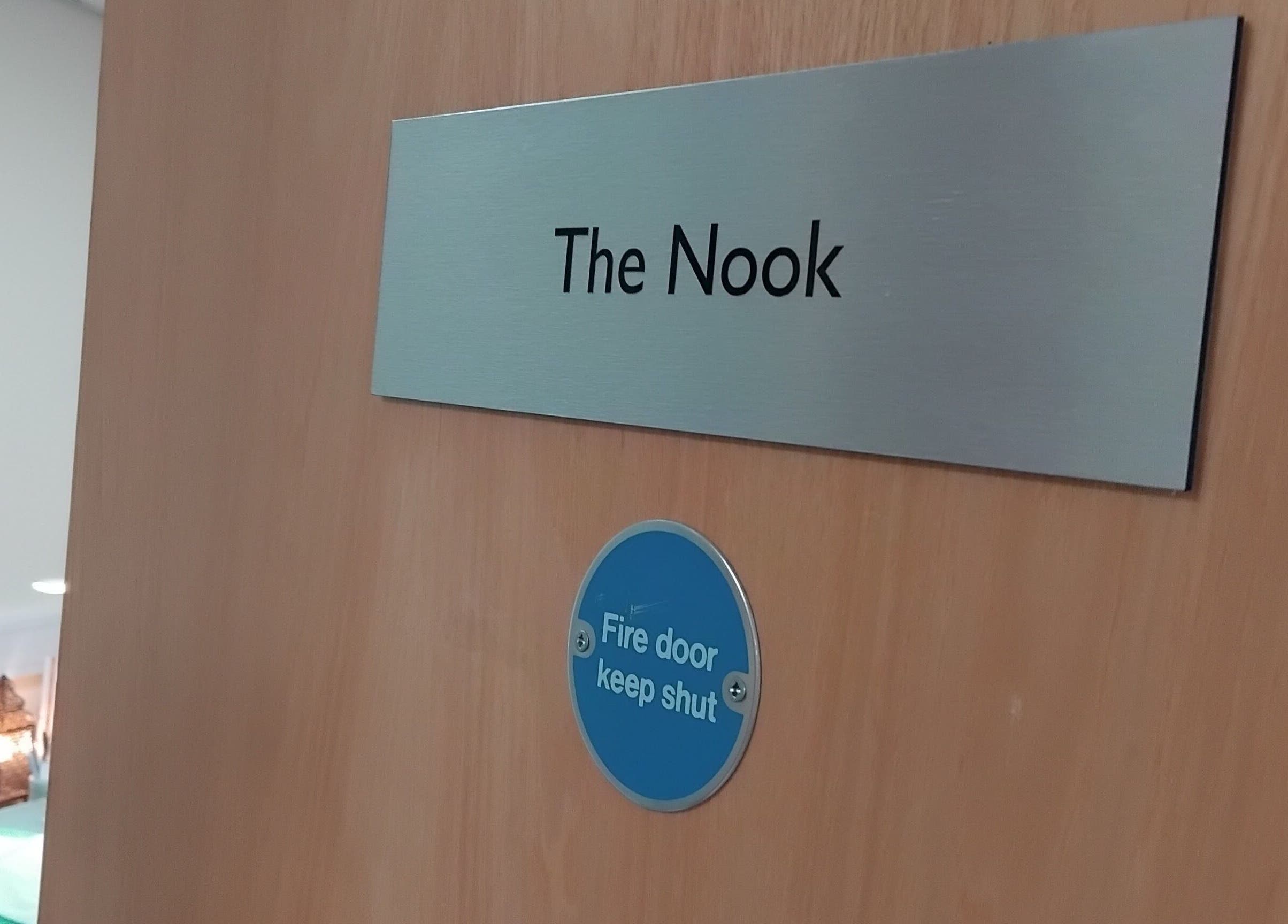 Entrance door to The Nook at Ellesmere Port, England, GB, showcasing a modern sign and safety notice.