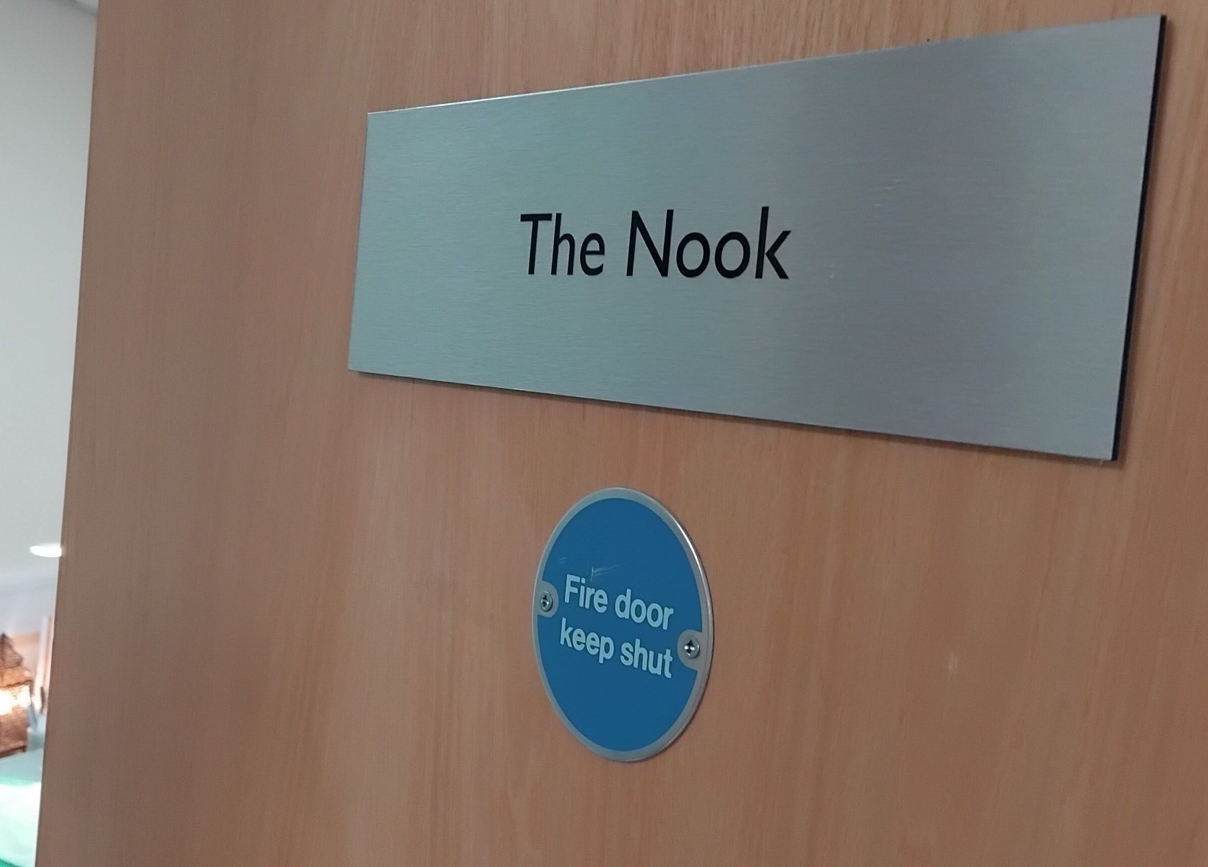 Entrance door to The Nook at Ellesmere Port, England, GB, showcasing a modern sign and safety notice.