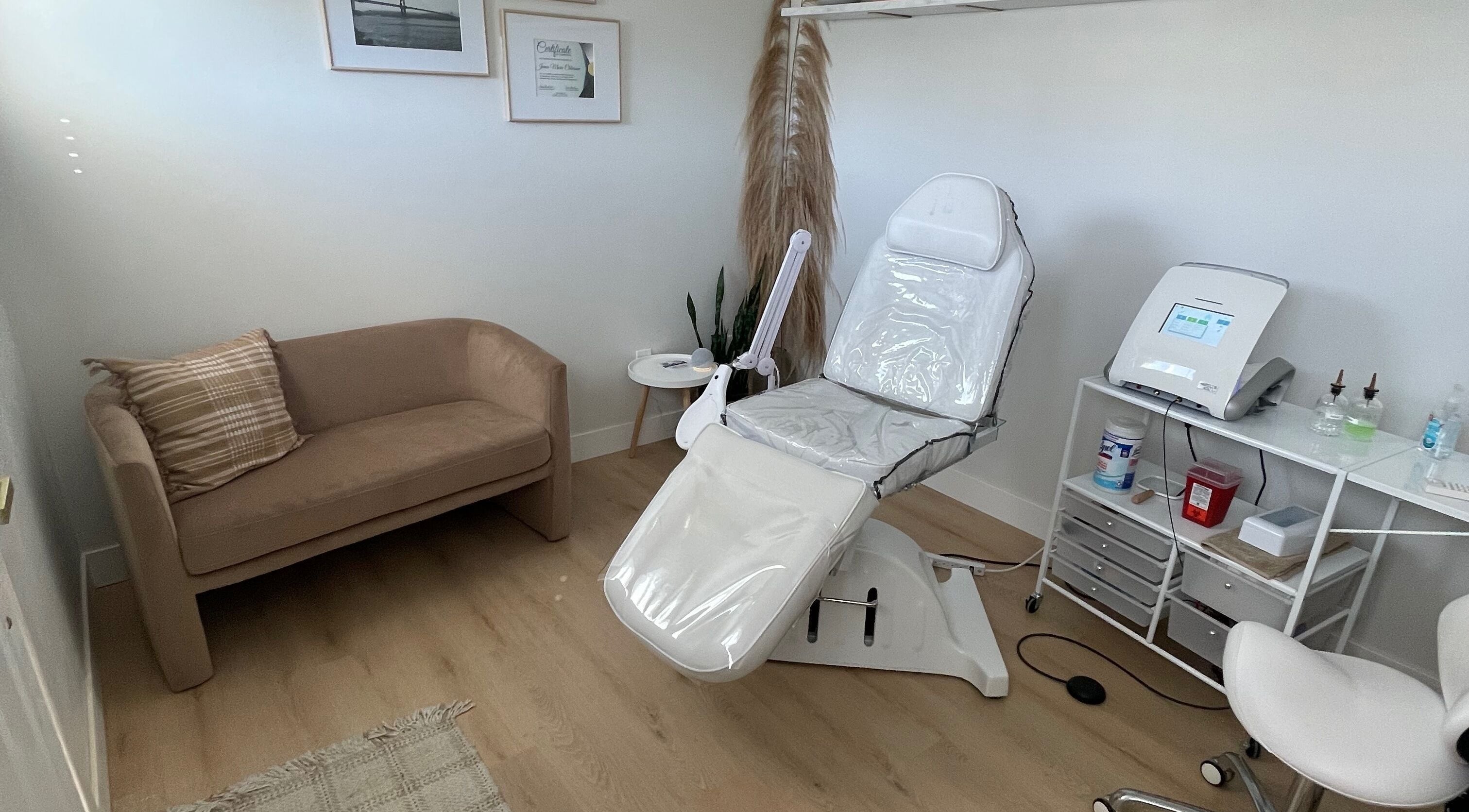 Calming treatment room at Silk Electrolysis in Herriman, Utah, US with a chair, sofa, and equipment.