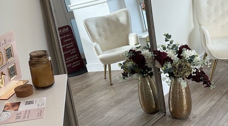 Elegant interior with a white chair at By Leah, Whitley Bay, England, GB, showcasing floral decor and a large mirror.
